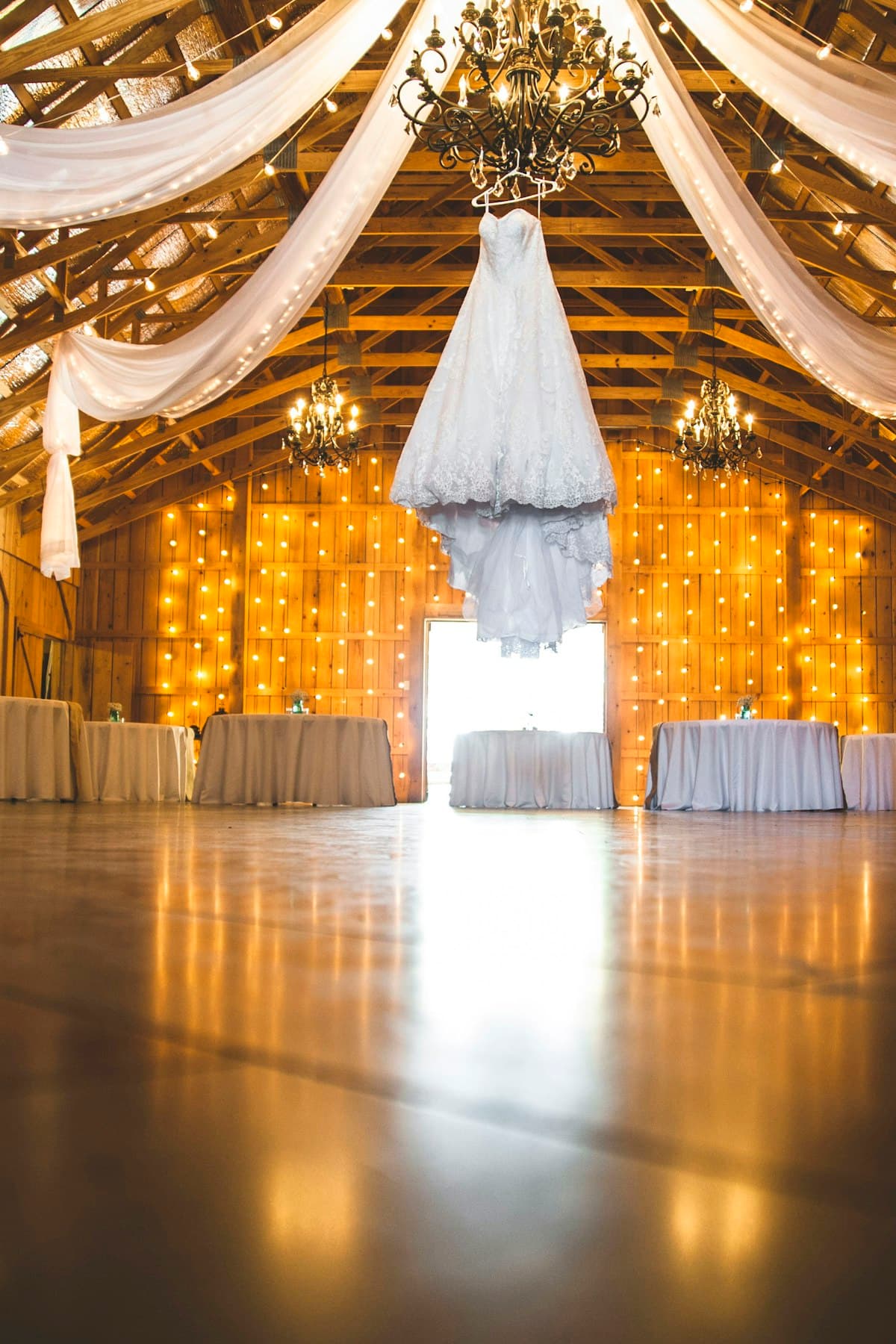 A warmly lit venue dressed with draped fabric and chandeliers